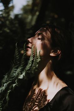 black and white photograph of woman with leaves on her face looking up to the sky