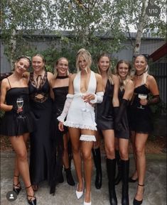 a group of women standing next to each other wearing short dresses and high heeled boots