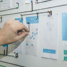 a man is pointing to the wall with pins on it