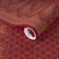 a red and gold carpet with an intricate design on the floor, it has a circular white object in the middle