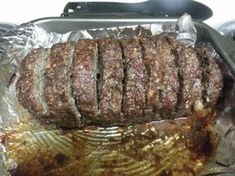 meatloaf sitting on top of foil in a pan with tongs next to it