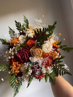 a person holding a bouquet of flowers in their hand with the background white and orange