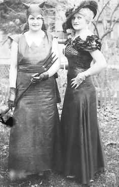 two women in dresses and hats standing next to each other