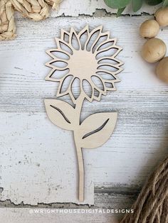 a wooden cutout of a sunflower on a white table next to some nuts