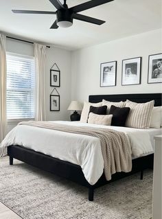 a bedroom with a bed, ceiling fan and pictures on the wall above it's headboard