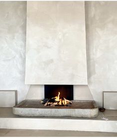 a fire place in the middle of a room with white walls and flooring on both sides