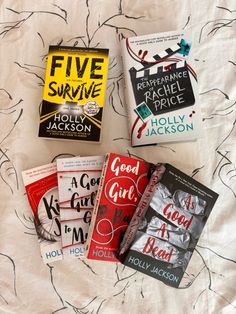 five books laid out on top of a bed next to each other in front of a white sheet