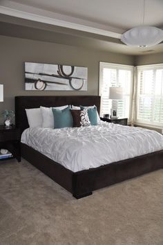 a large bed sitting in the middle of a bedroom next to a window with shutters