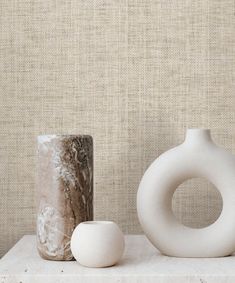 two white vases sitting on top of a table next to a stone ball and rock