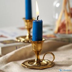 two blue candles sitting on top of a table next to a book and candle holder