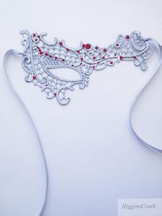 We offer original handcrafted embellishment designs for your mask. We can customize any mask to create a wearable work of art unique to you!Silver Masquerade Mask women Lace Red rhinestones Mardi Gras Mask These subtle yet seductive masks are each intricately embroidered to be a gorgeous addition to any costume or party dress that will transform you into a mystifying beauty of the night!  This pattern compliments all face shapes and is very comfortable to wear. Its also ideal to wear with eye gl Silver Rhinestone Eye Masquerade Mask, Silver Rhinestone Eye Mask For Masquerade, Red Eye Mask As Gift, Red Eye Mask For Gift, Red Eye Mask As A Gift, Silver Masquerade Mask With Rhinestones For Costume Party, Silver Rhinestone Masquerade Mask For Costume Party, Elegant Silver Masks As Gift, Handmade Red Masquerade Mask