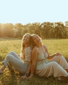 two women sitting on the ground in a field