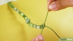 someone is making a beaded bracelet with green and white beads on the end of it