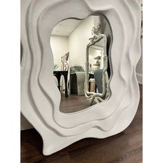 a large white mirror sitting on top of a wooden floor