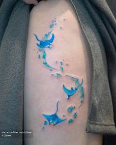 a woman's thigh with blue paint splattered on it and birds flying around