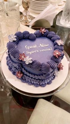 a purple cake sitting on top of a glass plate covered in frosting and flowers