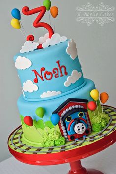 a thomas the train themed birthday cake with balloons and numbers on it's top