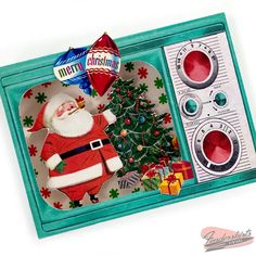 a christmas card with santa clause on it in a box next to a tree and an old fashioned washing machine