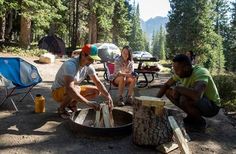 some people are camping in the woods with their camp stoves and picnic tables around them