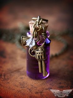 a small purple bottle with a cross on it and a chain hanging from the top