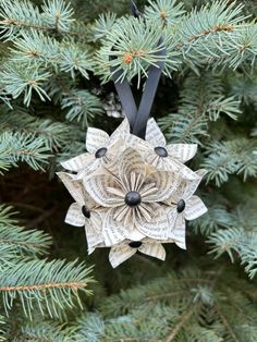 an ornament made out of newspaper sits on top of a pine tree branch