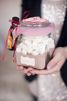 a person holding a jar filled with marshmallows