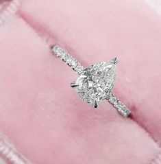 a diamond ring sitting on top of a pink velvet box