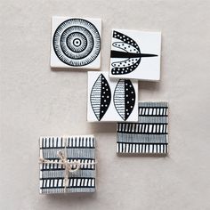 four ceramic coasters with black and white designs on them