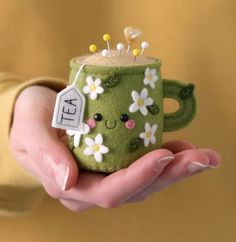 a hand holding a green coffee mug with flowers on it