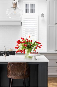 red tulips are in a vase on the kitchen island