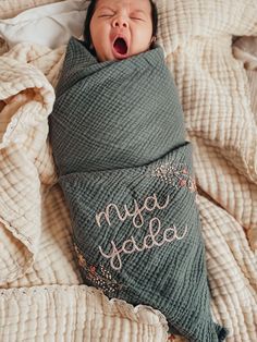 a baby wrapped in a blanket with its mouth open