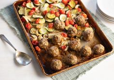 a pan filled with meatballs and vegetables on top of a table