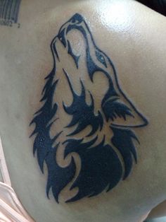 a wolf tattoo on the back of a person's shoulder