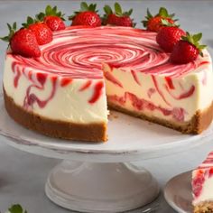 a strawberry swirl cheesecake on a cake plate with one slice cut out to show the inside