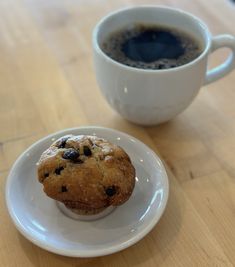 a muffin on a plate next to a cup of coffee