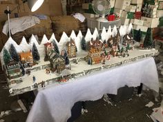 a table topped with lots of small christmas village figurines on top of snow covered ground