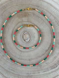 a necklace with multi colored beads and a gold plated clasp on a silver background