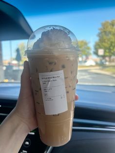 a person holding up a cup of iced coffee in their hand with a receipt attached to it