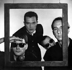 three men in suits and sunglasses are looking through a mirror with their hands on the frame