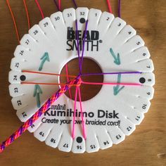 there is a clock made out of strips of paper and some thread on the table