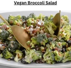 a white plate topped with broccoli salad next to a wooden spoon filled with dressing