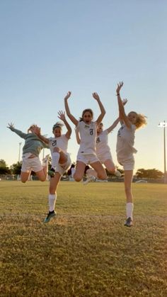 four girls jumping in the air on a soccer field