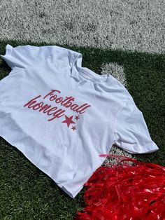 Show your team spirit with our White Cropped T-Shirt, featuring a trendy graphic that says “Football Honey” in bold red lettering. This chic, elegant, boujee, and trendy preppy design is perfect for making a statement on college or professional game days and at tailgate parties. The cropped fit adds a modern, stylish edge, ensuring you stay comfortable and fashionable while cheering on your favorite team. **Key features:**- Chic, elegant, boujee, trendy preppy design- “Football Honey” graphic in bold red lettering- Stylish cropped fit- Soft, comfortable white fabric- Perfect for college and professional game days, and tailgate parties **Keywords:** White Cropped T-Shirt, Football Honey T-Shirt, Trendy Game Day Fashion, Chic Preppy Shirt, Elegant Boujee Style, College Game Day Apparel, Prof Sporty Tops With Team Name For College Events, School Spirit Slogan Top For Game Day, Red Tops For Cheerleading During Sports Season, Sporty Letter Print Tops For College Events, Varsity Tops With Team Name For College Events, Sporty Tops With Letter Print For College Events, Graphic Print Tops For College Events With Team Spirit, Team Spirit Graphic Print Tops For College Events, White Varsity Top For College Events