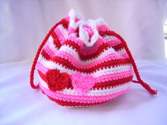 a crocheted pink and white purse with red hearts on it's side