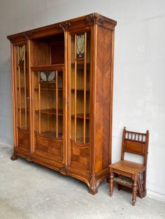 an old wooden china cabinet next to a chair