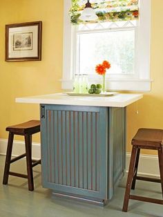 a small kitchen island with stools in front of it and a window behind it