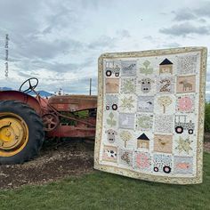 an old tractor is parked next to a quilt that has been hung on the back of it