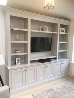 a living room with white bookcases and a flat screen tv