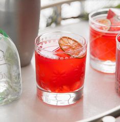 three glasses filled with red liquid sitting on top of a table