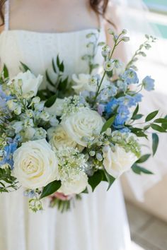 a bride holding a bouquet of white and blue flowers